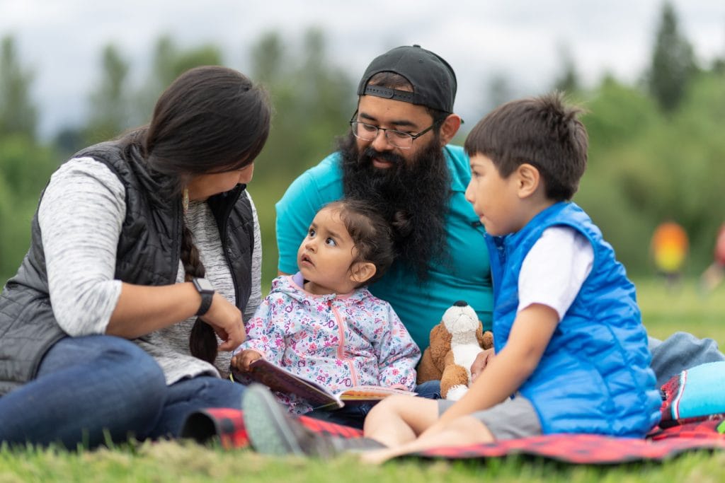 A family hanging out at the park and reading together