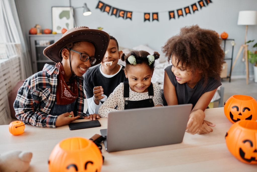 kids in Halloween costume using a computer