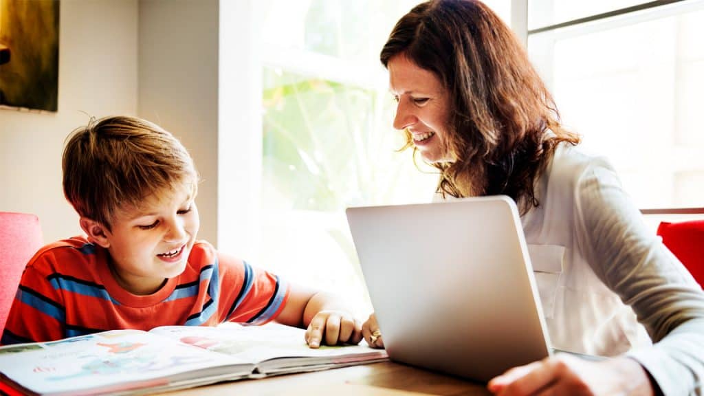 A boy and his caregiver use a laptop to do homework