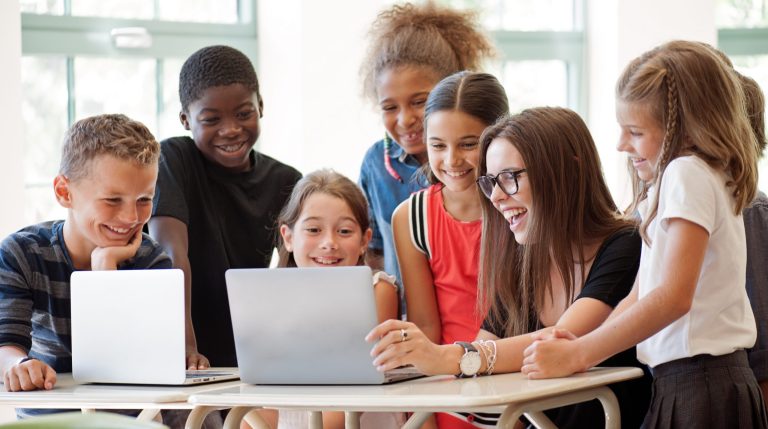 students using laptop with teacher in the classroom