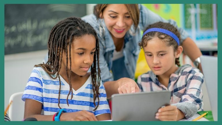 a teacher working with two students on a laptop