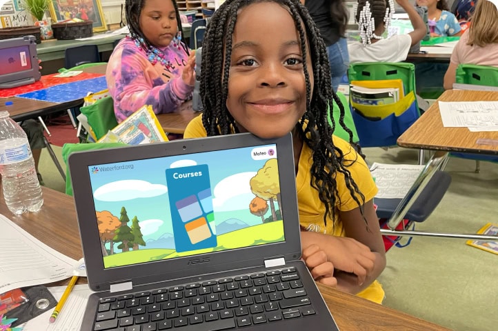 girl smiling in front of a Waterford activity on a laptop