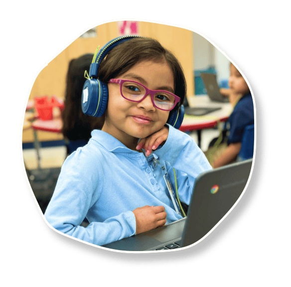 Student with headphones smiling and working on laptop